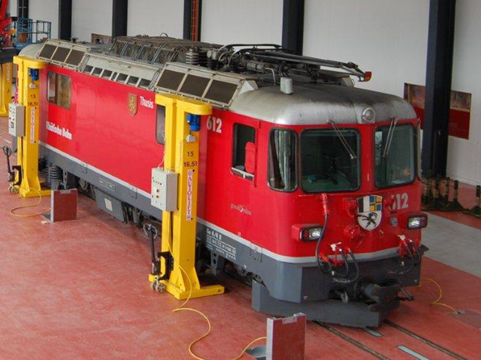 Red train on hydraulic lifts in workshop with wireless CAN data radio systems for secure communication