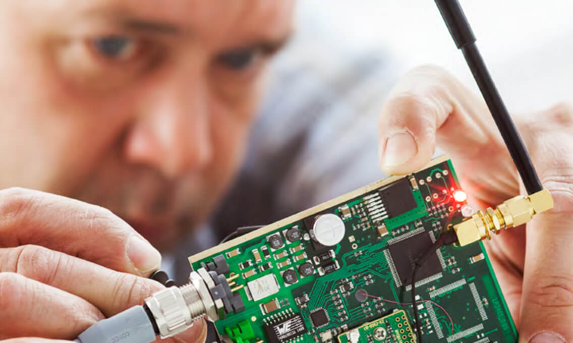 Hand holds green circuit board and antenna as a symbol for wireless and reliable wireless data technology from Schildknecht AG
